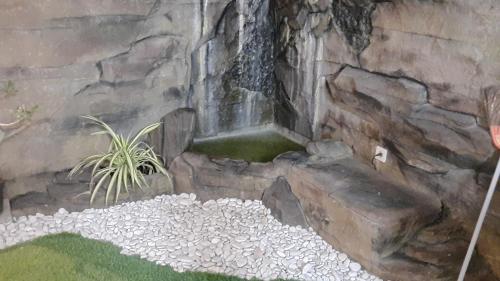 a stone wall with a waterfall in a garden at Guest House Omah Ningrat Surabaya in Surabaya