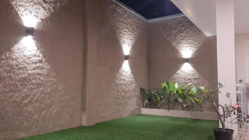 Zimmer mit einer Wand mit Beleuchtung und grünem Boden in der Unterkunft Guest House Omah Ningrat Surabaya in Surabaya