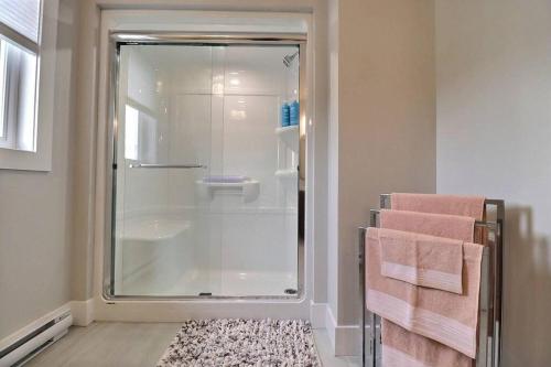 a bathroom with a shower with towels and a rug at Beautiful Home in Moncton North! in Moncton