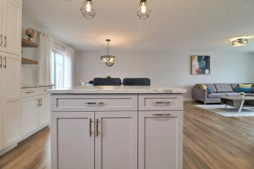 a kitchen with white cabinets and a living room at Beautiful Home in Moncton North! in Moncton