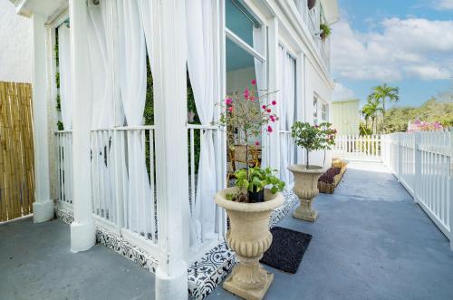 a porch with white curtains and potted plants on it at The Golden Alligator 1 - 3 beds 2 baths in West Palm Beach close to everything in West Palm Beach