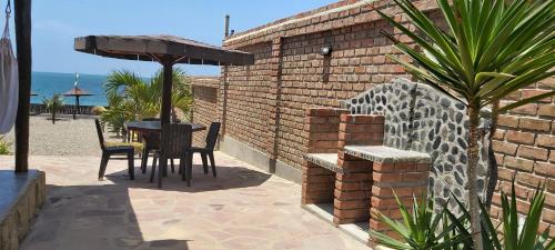 a patio with a table and chairs and an umbrella at Guille Bungalows in Canoas De Punta Sal