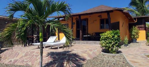 a house with a palm tree in front of it at Guille Bungalows in Canoas De Punta Sal