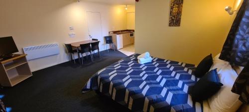 a room with a bed with a blue cover on it at New Castle Motor Lodge in Rotorua