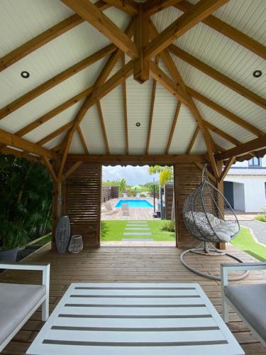 a patio with a roof with a swing and a pool at VILLA ALOEREVE in Sainte-Anne