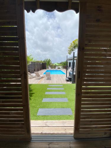 a view of a yard with a pool through a door at VILLA ALOEREVE in Sainte-Anne