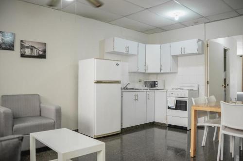 a kitchen with white cabinets and a table and a chair at Cardedeu Suites in San Salvador