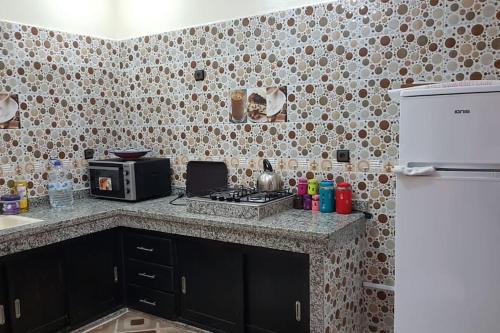 eine Küche mit einer Theke mit einem Herd und einem Kühlschrank in der Unterkunft Appartement RDC in El Jadida