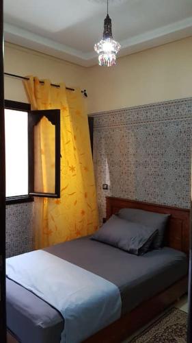 Schlafzimmer mit einem Bett, einem Fenster und einem Kronleuchter in der Unterkunft Appartement RDC in El Jadida
