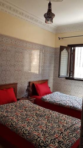 a bedroom with two beds with red pillows at Appartement RDC in El Jadida