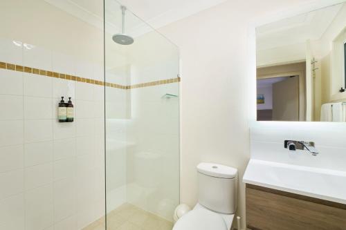 a bathroom with a shower and a toilet and a sink at Flynns on Surf Beach Villas in Port Macquarie