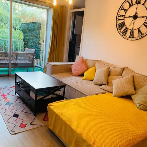 un salon avec un canapé et une horloge au mur dans l'établissement Appartement entier vue dégagée avec parking, à Montpellier