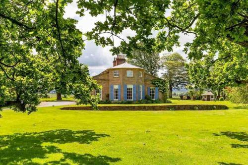 a large house with a green yard with trees at Luxury Scottish Manor house + jacuzzi + bbq cabin + helipad in Maybole