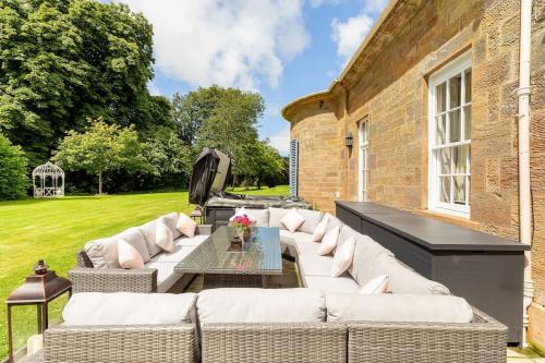 a patio with white couches and a table at Luxury Scottish Manor house + jacuzzi + bbq cabin + helipad in Maybole