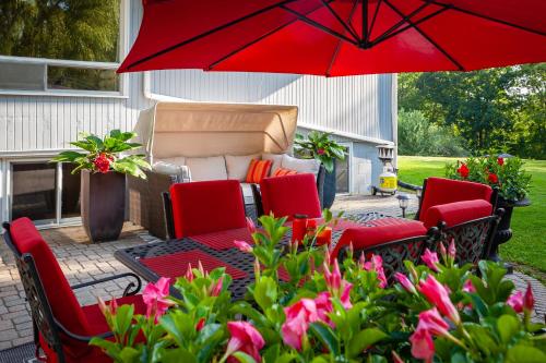 eine Terrasse mit roten Stühlen und einem roten Regenschirm in der Unterkunft Nature Oasis BarMar 2BR Suite in Dundas close to Webster Falls in Dundas