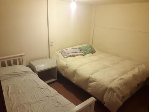 een kleine slaapkamer met 2 bedden en een nachtkastje bij Departamento Mí Sueño in Ushuaia