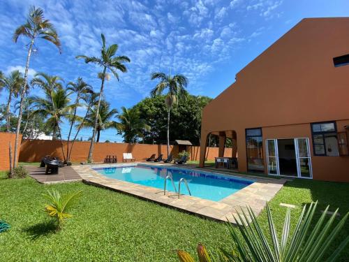 uma piscina em frente a uma casa com palmeiras em Pousada Ponta dos Corais no Guarujá