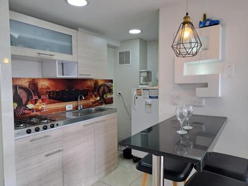 a kitchen with white cabinets and a black counter top at Apartamento moderno cerca del aeropuerto in Bogotá