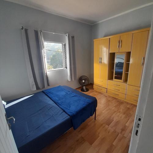 Un dormitorio con una cama azul y una ventana en Casa no centro en Pirapora do Bom Jesus