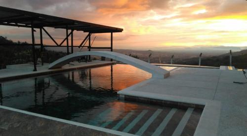 una piscina con puesta de sol en el fondo en FINCA LA FORTALEZA, en Santa Rosa de Cabal