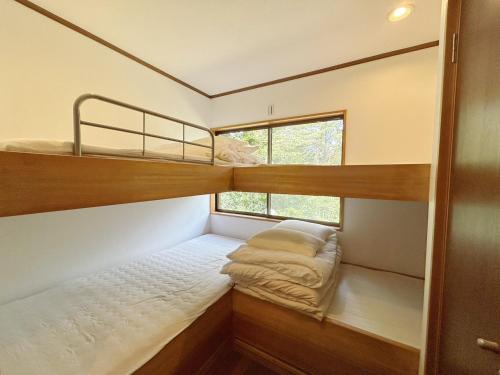 2 Etagenbetten in einem kleinen Zimmer mit Fenster in der Unterkunft フォレストハウス伊豆箱根 in Kannami
