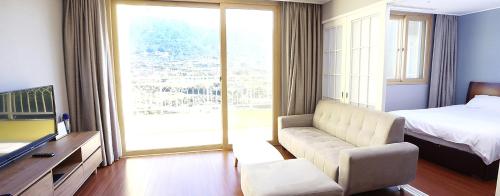 The K Jirisan Family Hotel في Gurye: غرفة معيشة بها أريكة وسرير ونافذة