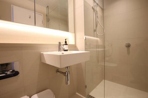 y baño blanco con lavabo y ducha. en Great location 2B1B free parking, en Melbourne