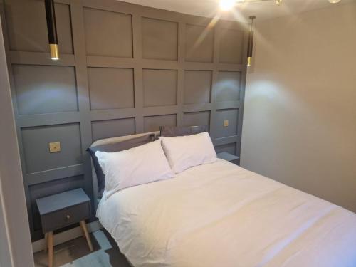 Bett mit weißer Bettwäsche und Kissen in einem Zimmer in der Unterkunft Collier's Wood en-suite apartments in London