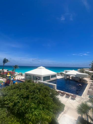 a resort with a pool and the ocean in the background at Hermoso Depto con vista al mar en zona hotelera. in Cancún
