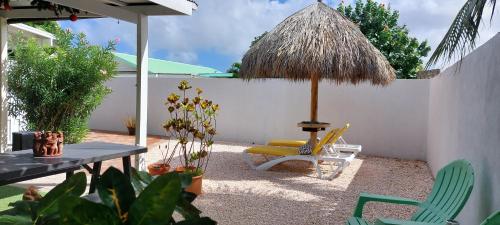 a patio with a chair and an umbrella and a table at Dancing Iguanas in Oranjestad