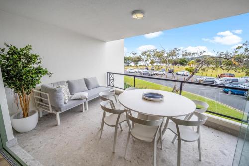 a balcony with a table and chairs and a couch at Bay Royal Apartments in Byron Bay