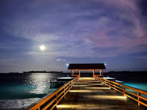 a dock with a building on the water at night at Andau Resort Raja Ampat in Tapokreng