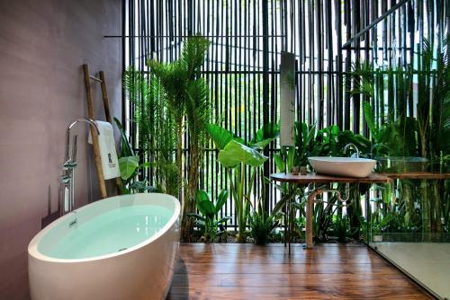 ein Bad mit einer Badewanne und Pflanzen in der Unterkunft AnNam Village in Vũng Tàu