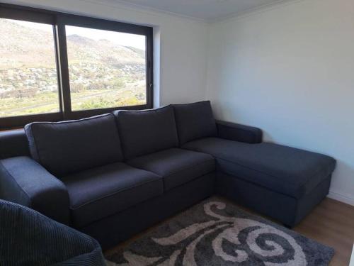 a living room with a blue couch and a window at Modern mountainside home with ocean view - Minimal load shedding in Cape Town
