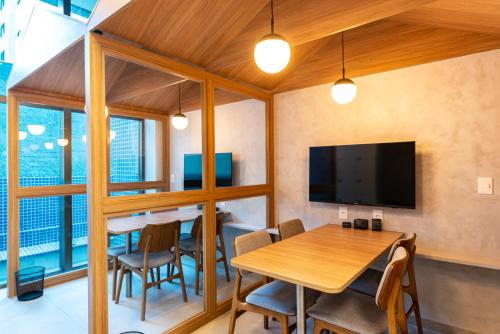 a dining room with a table and a tv at Flat luxo em Boa Viagem Rooftop 201 in Recife