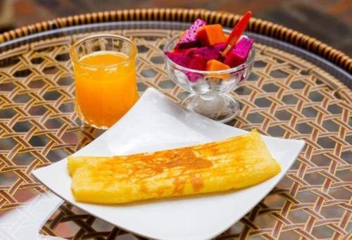 a plate of food and a bowl of fruit and a drink at Dear Villa House in Luang Prabang