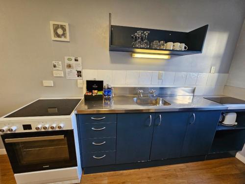 a blue kitchen with a sink and a stove at Hacienda Motor Lodge in Palmerston North