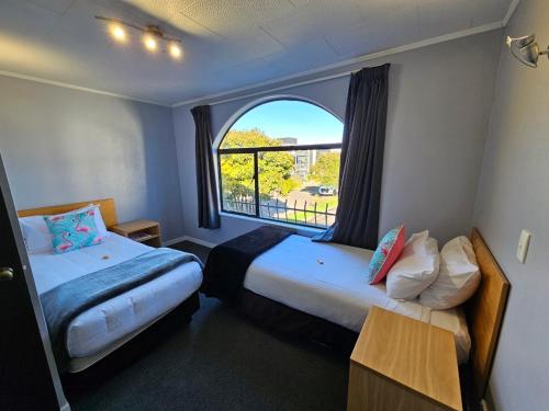 Habitación de hotel con 2 camas y ventana en Hacienda Motor Lodge, en Palmerston North