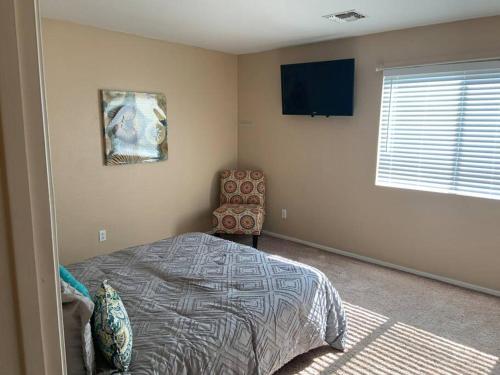 a bedroom with a bed and a chair and a television at Bella Oasis Family Retreat in El Mirage