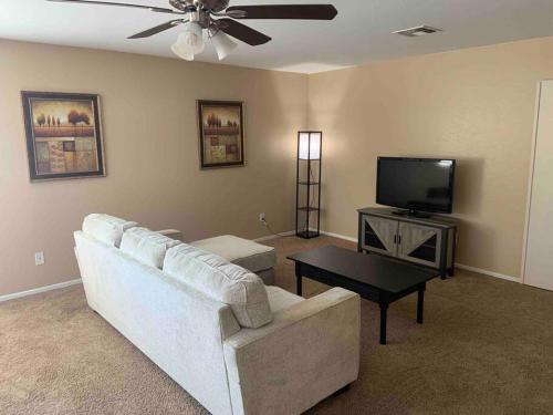 a living room with a white couch and a tv at Bella Oasis Family Retreat in El Mirage