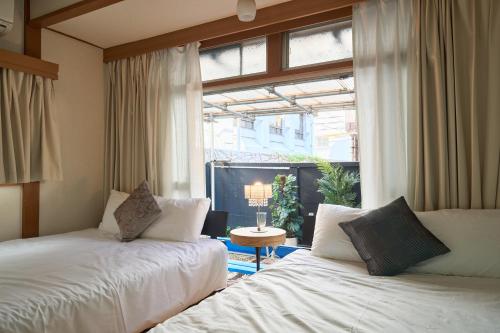 two beds in a room with a large window at Total 107square meter 4min to nearest staion Max16pp in Tokyo