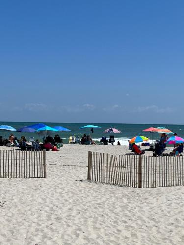 a beach with umbrellas and people sitting on the beach at Ocean Dream Vacation in Myrtle Beach
