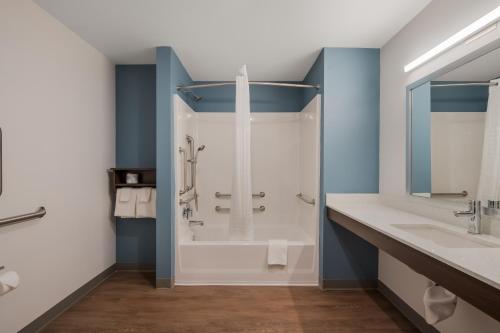 a bathroom with a shower and two sinks at WoodSpring Suites Bellflower - Los Angeles in Bellflower