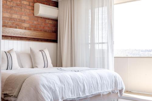 a bedroom with a white bed and a brick wall at Hillcrest Merimbula in Merimbula