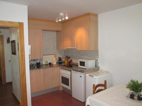 a kitchen with wooden cabinets and a white microwave at Al Rincon de Emi in Carreña de Cabrales