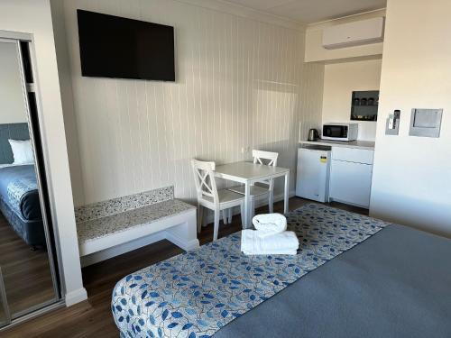 a small room with a kitchen and a table with a bed at Surf Beach Motel Newcastle in Newcastle