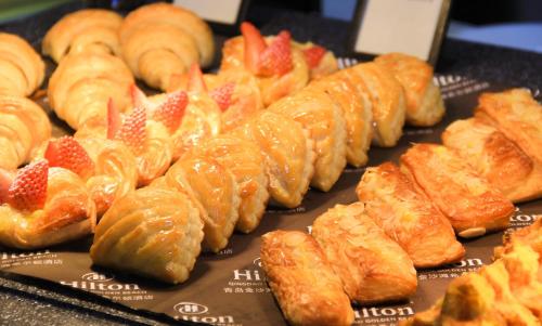 a bunch of pastries and croissants on a table at Hilton Qingdao Golden Beach - Beer Halls in Huangdao