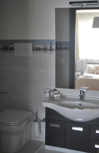 a bathroom with a sink and a toilet and a bed at Pietra Bianca Rooms in Pachino