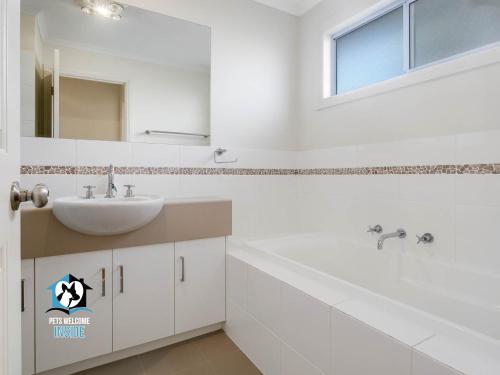 维克多港Light Filled Modern & Stylish 3BR Holiday Home的带水槽和镜子的白色浴室