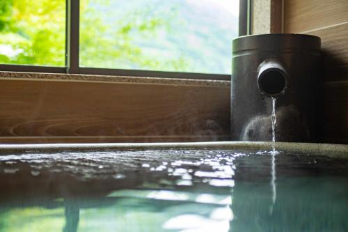 a water fountain in a room with a window at Senkei in Hakone